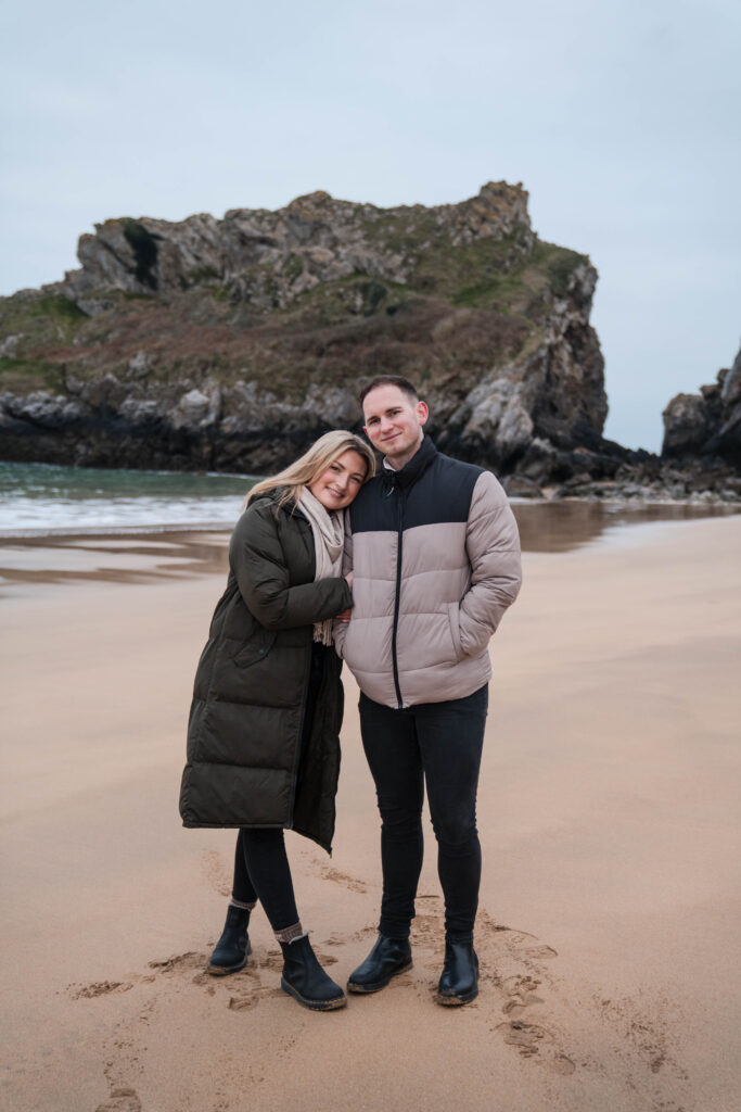 Black and white photo at engagement photoshoot.  Couple running on the beach at Broad Haven South, Pembrokeshire, West Wales. 