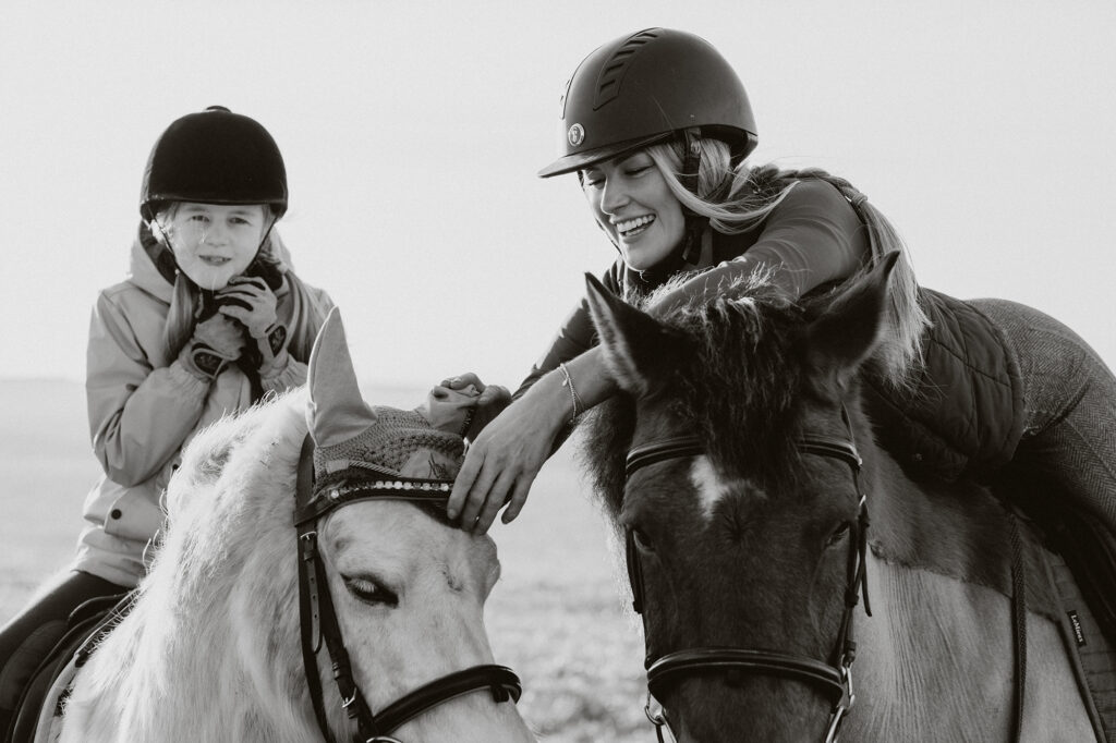 black and white family photoshoot in St Davids, Pembrokeshire, with a mother and daughter riding horses at sunset on the coast