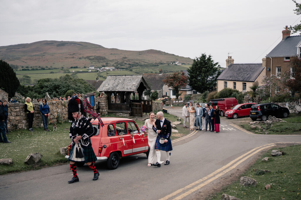 A relaxed Llangennith wedding in Gower featuring beach photos, a Welsh choir, bagpipes, a Morris Minor, a village hall reception and a lively ceilidh.